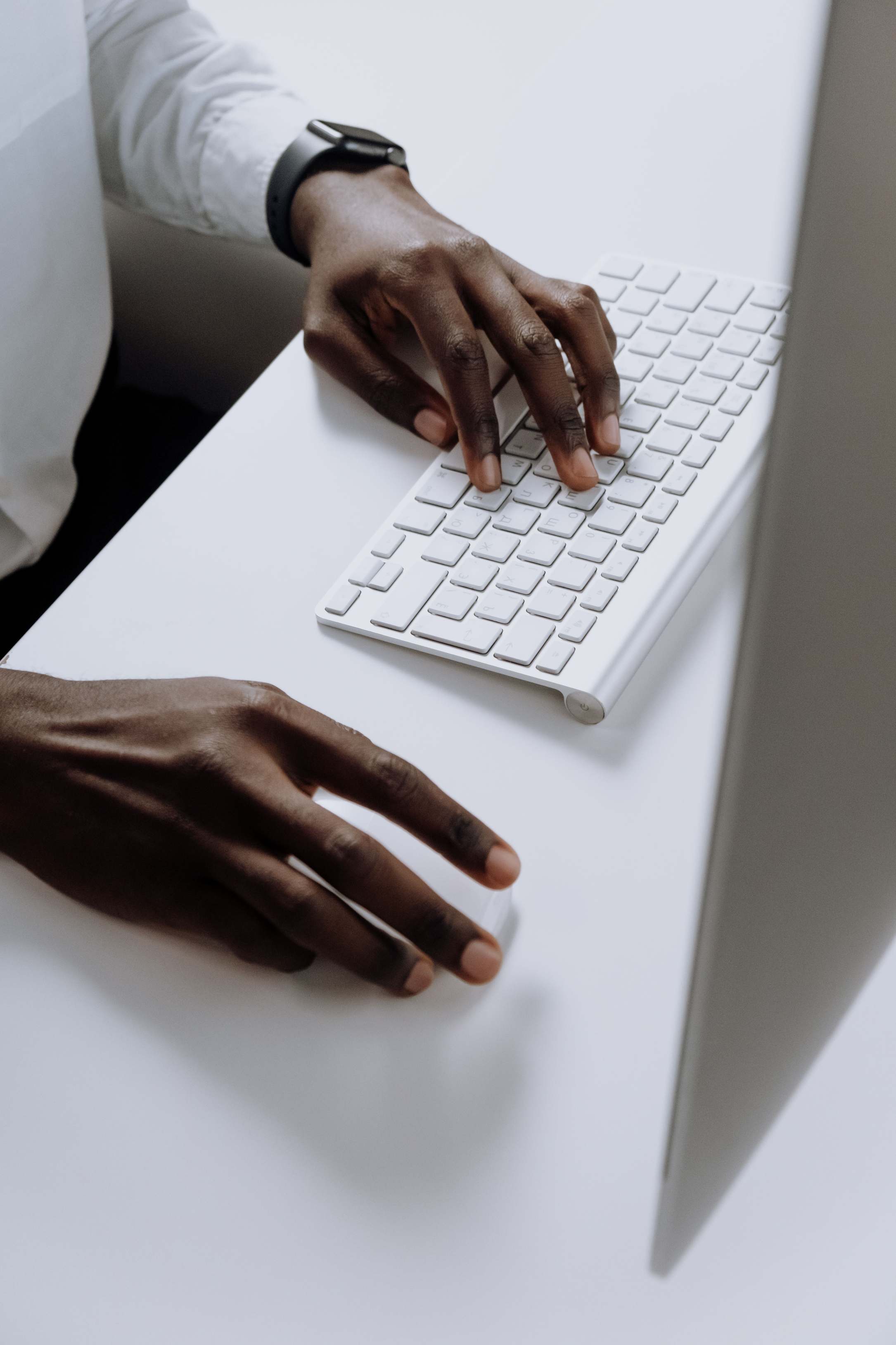 Nahaufnahme von Händen an Laptop-Tastatur — Monitor im Hintergrund
